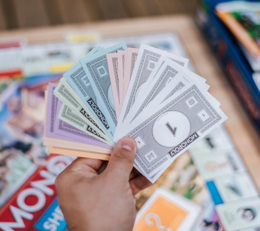 hand holding monopoly money with a monopoly board in the background