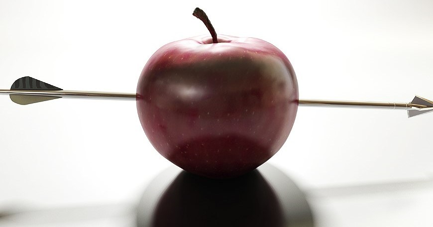 red apple sitting on white background with a metal arrow through the center