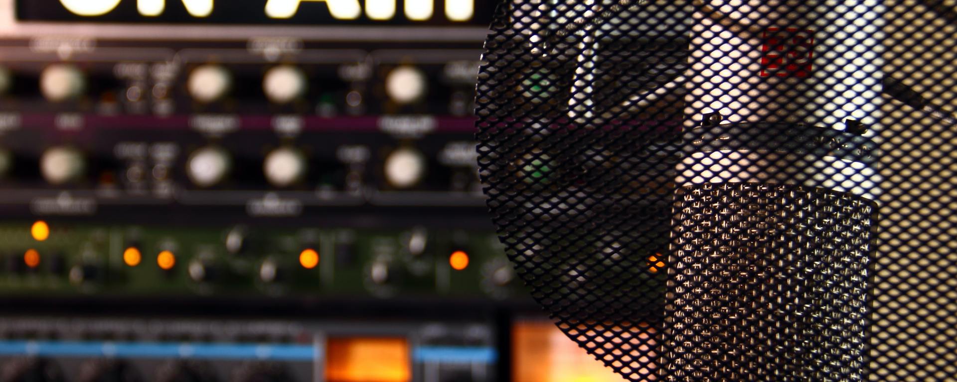 lit "ON AIR" sign above a switchboard with a microphone in front