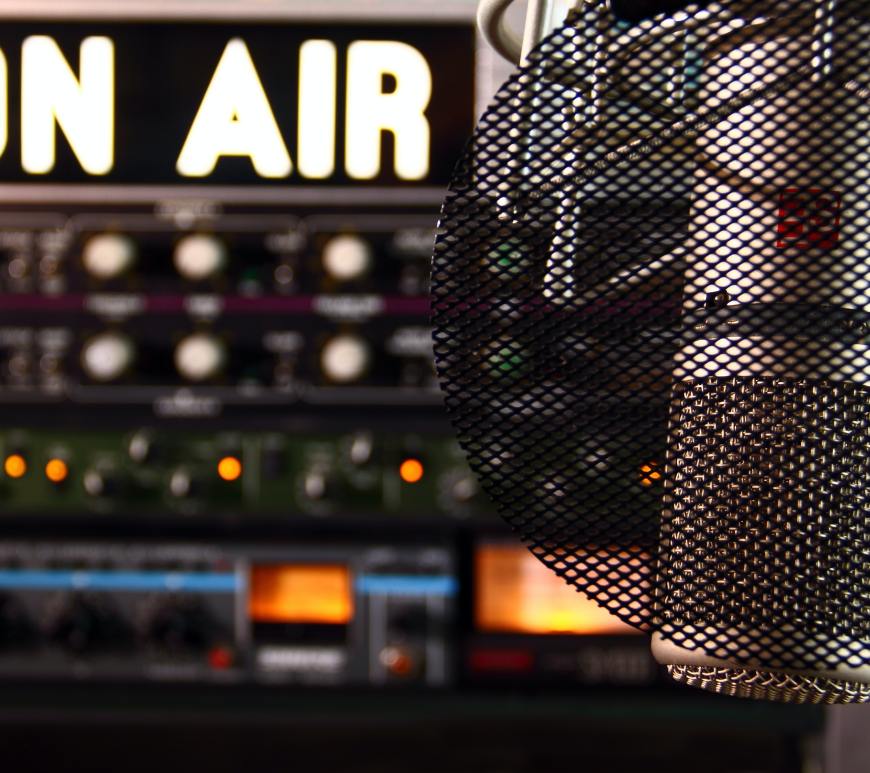 lit "ON AIR" sign above a switchboard with a microphone in front