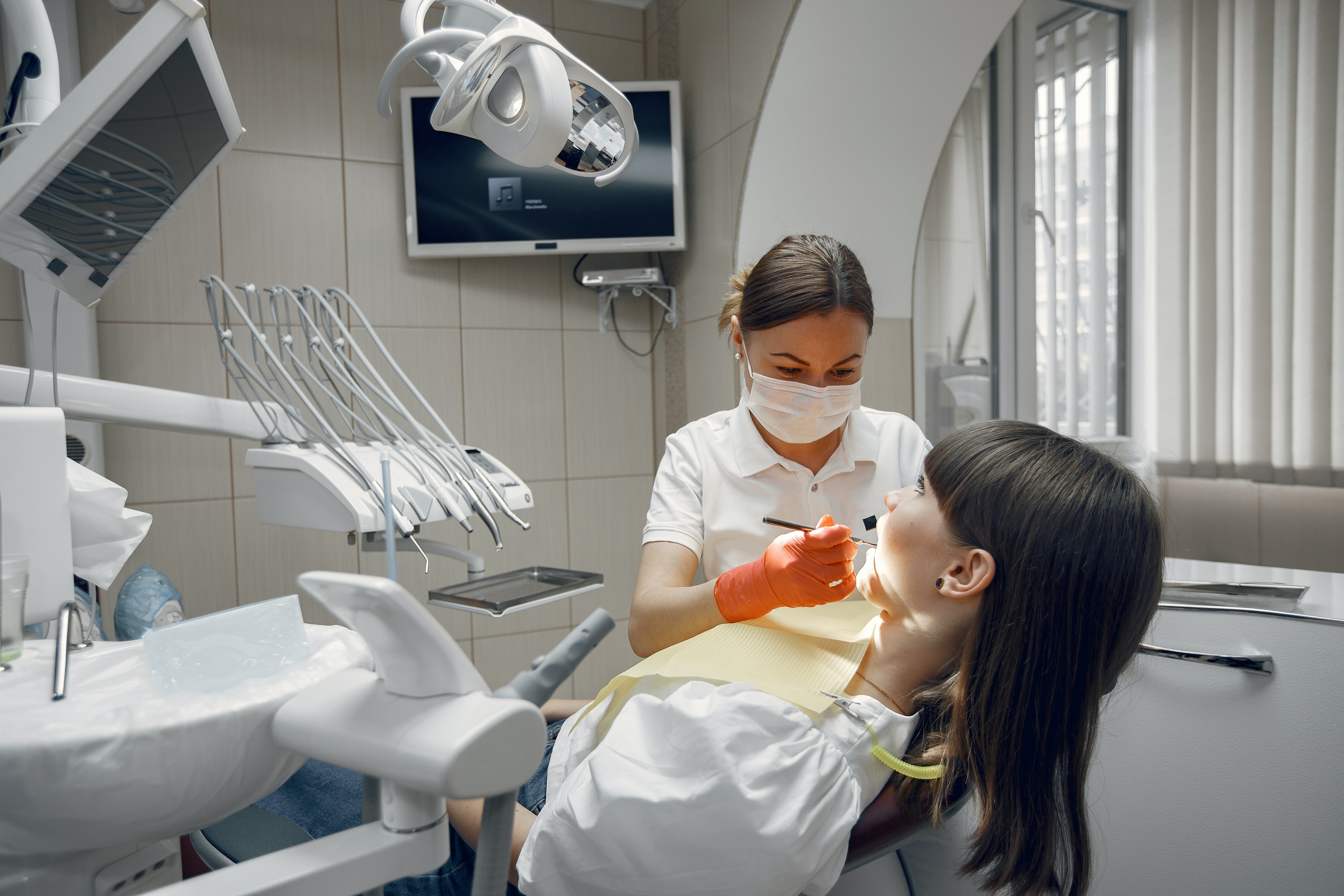 woman in dentists chair with dentist using dental apparatus in her mouth