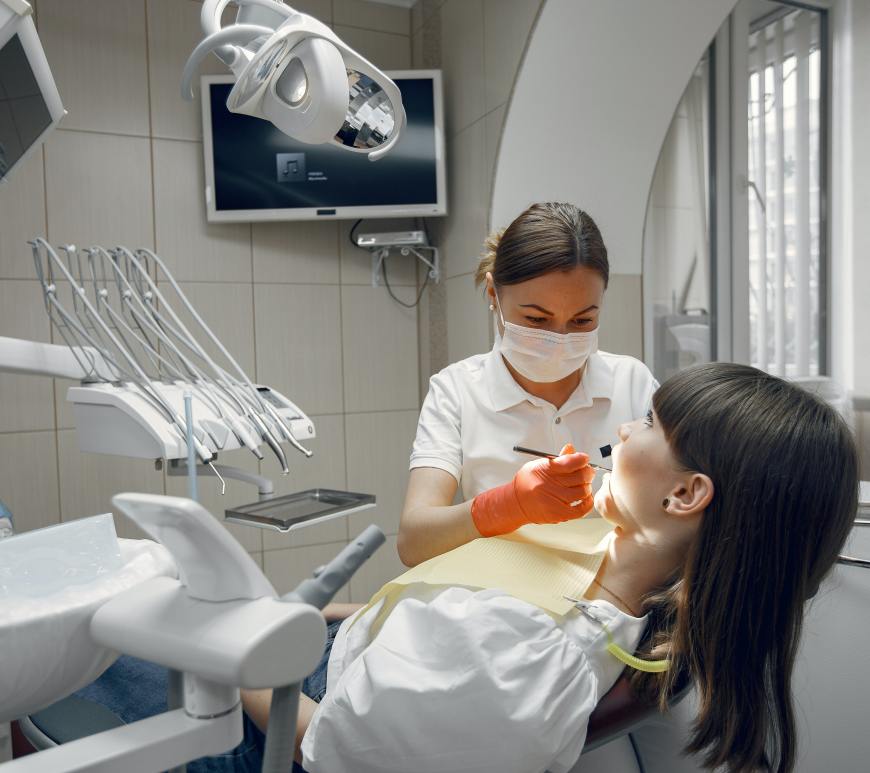 woman in dentists chair with dentist using dental apparatus in her mouth