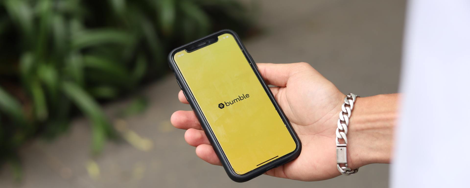 hand holding smartphone with bumble logo on screen