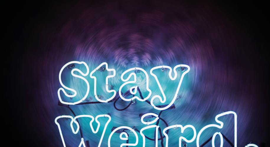 neon sign that says "stay weird." on a dark background