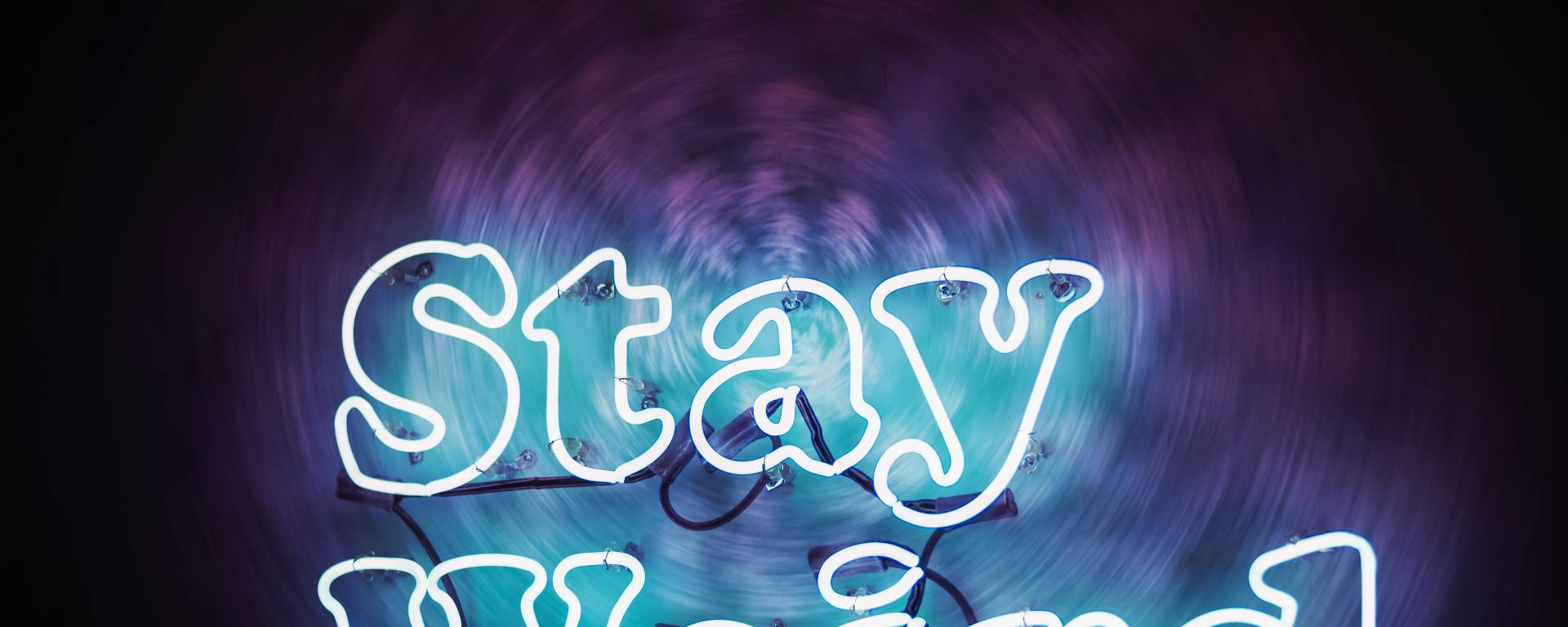 neon sign that says "stay weird." on a dark background