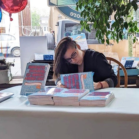 Renata Leo signing a copy of her book "Unapologetic Oversharing, Self-Awareness, & Buffalo Sauce"